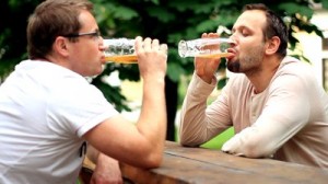 two-male-friends-talking-and-drinking-beer-outdoors